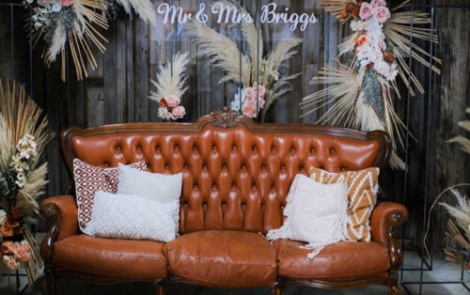 A Leather Vintage Couch styled with florals for a wedding backdrop